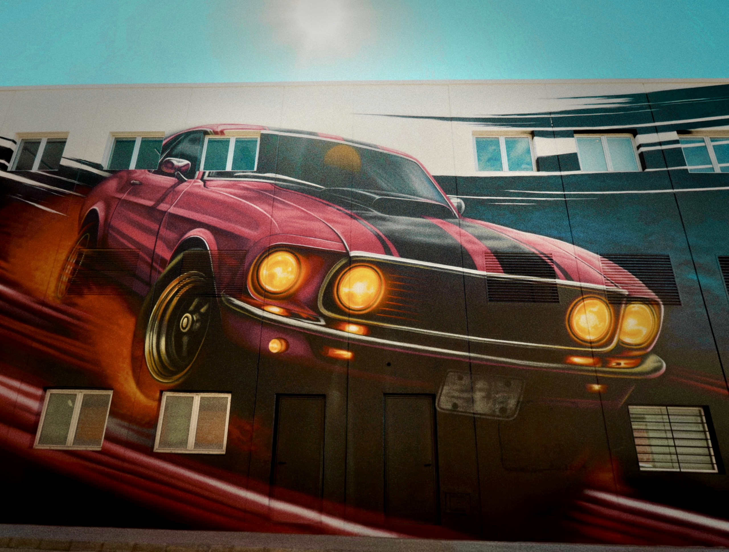 Fachada del Sky Business Center de Manises pintada con el mural del coche clásico, obra de Keoni VGN