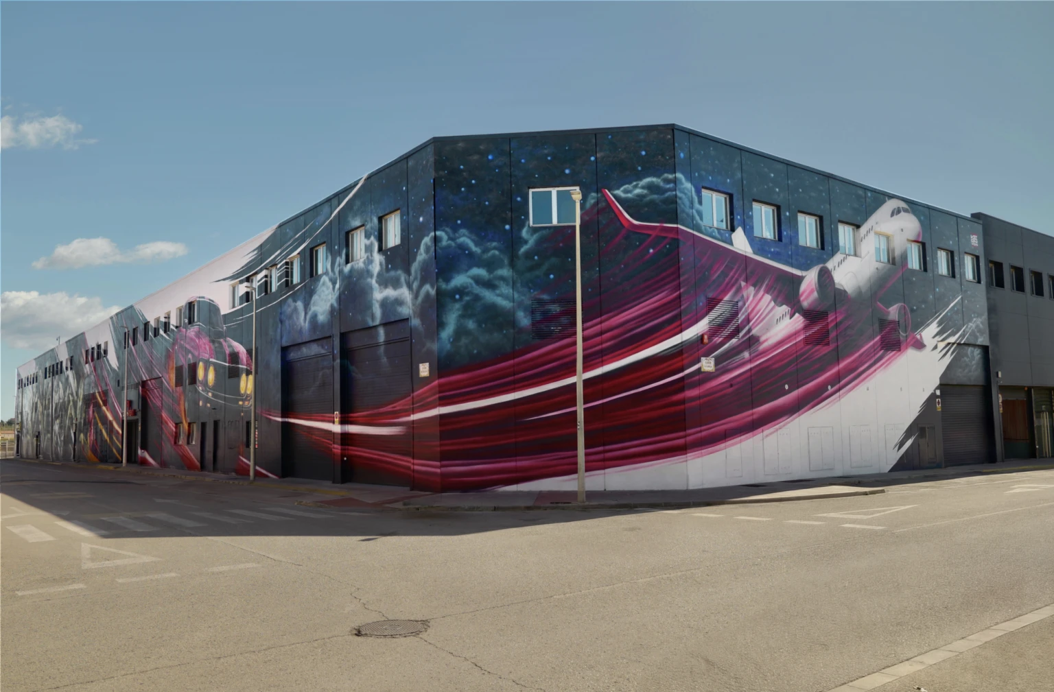 Fachada del Sky Business Center de Manises pintada con el mural del avión, obra de Keoni VGN