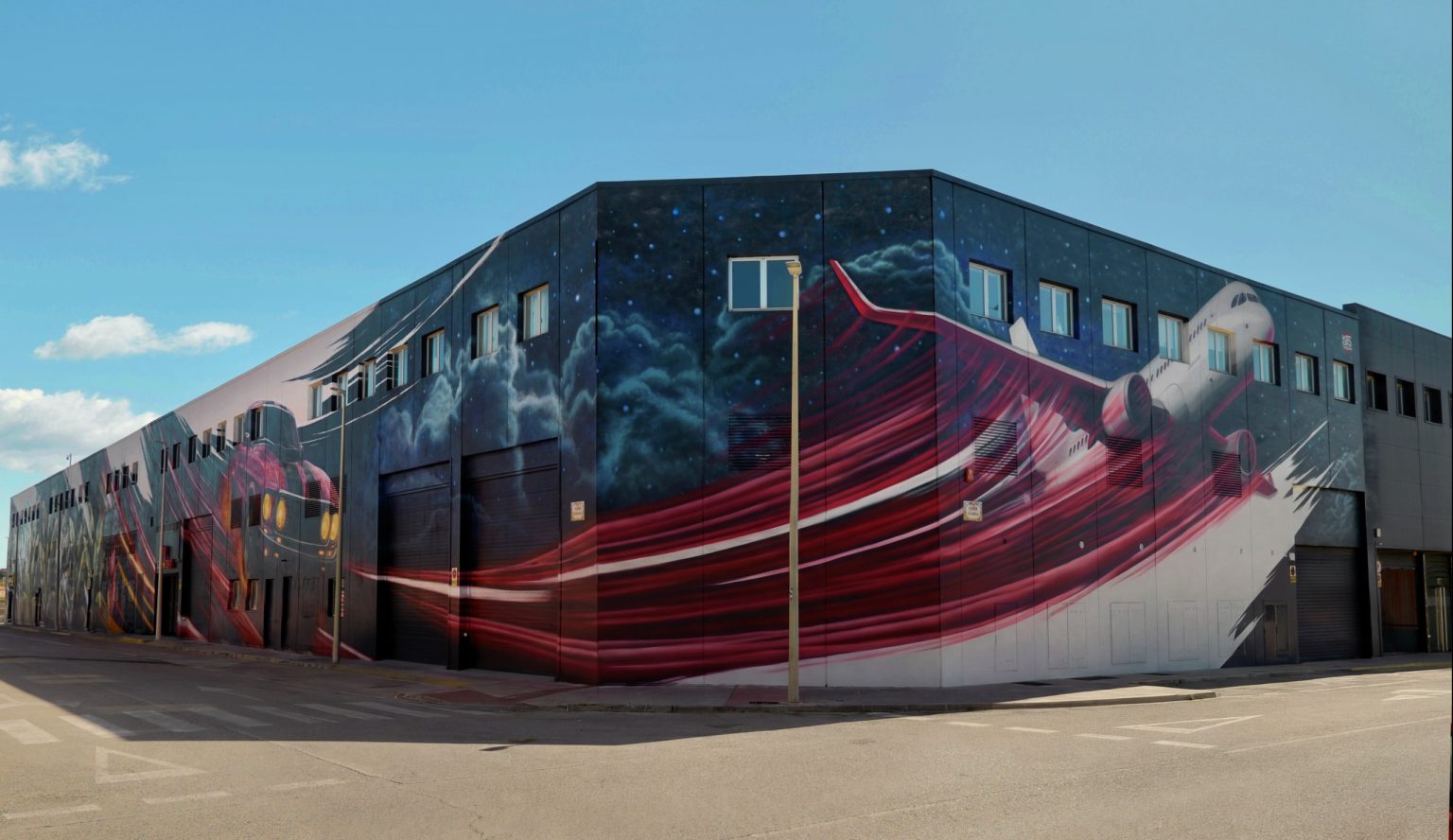 Fachada del Sky Business Center de Manises pintada con el mural del avión, obra de Keoni VGN